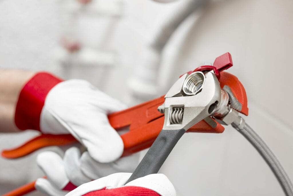Plumber holding pipe wrenches for an emergency repair in Colton
