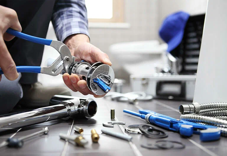 Technician repairing a plumbing fixture with professional tools in Colton