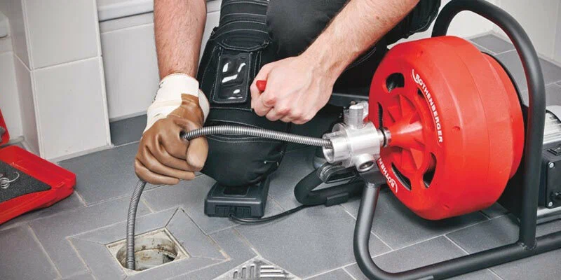 Plumber using a drain-cleaning machine in Colton