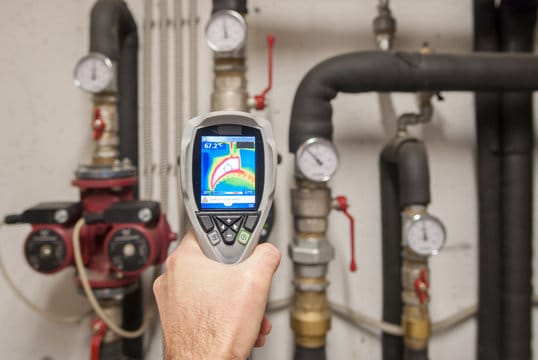 Plumber using a thermal imaging camera to inspect pipes in Colton