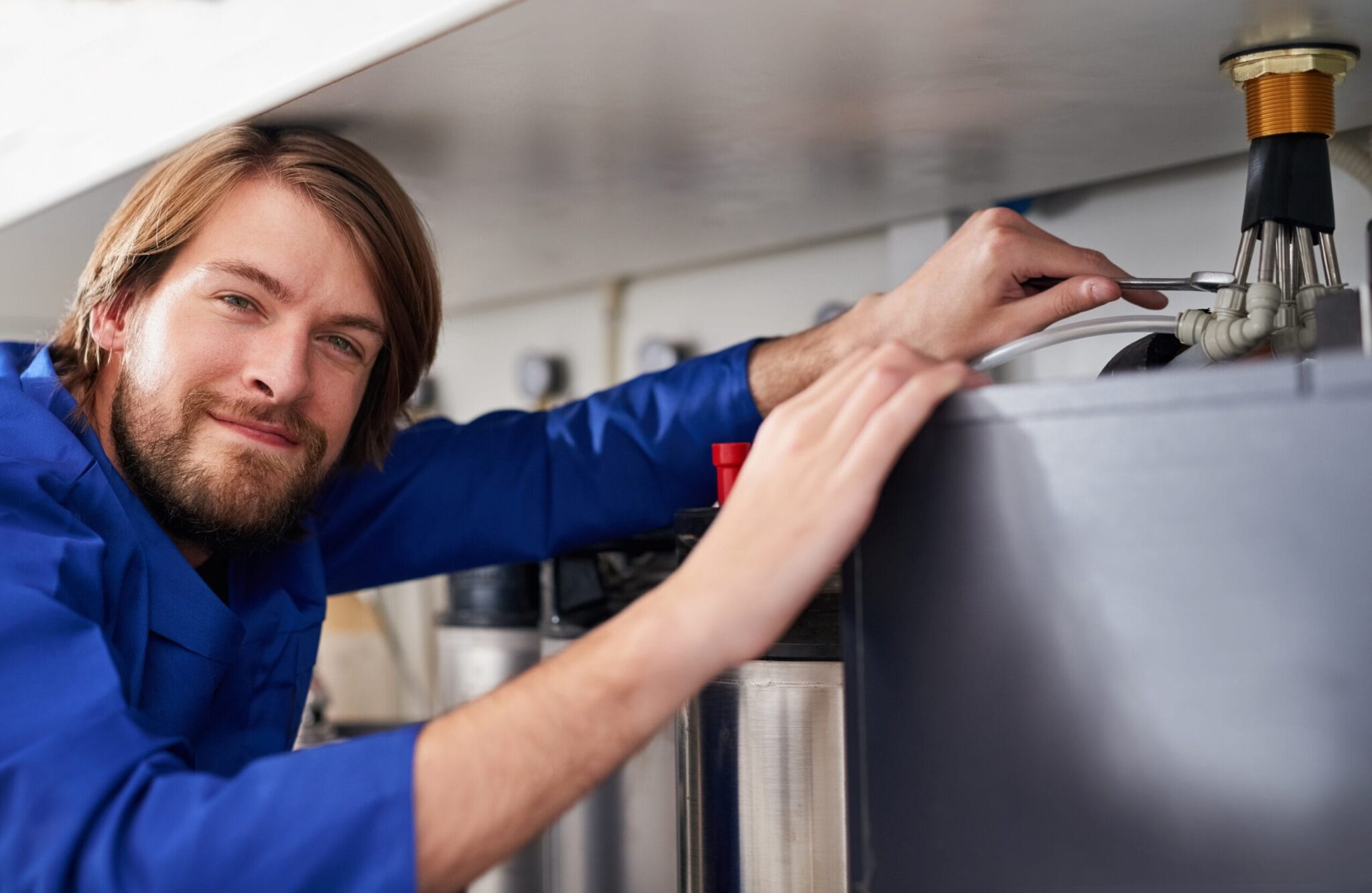 Technician servicing a residential water heater tank in Colton