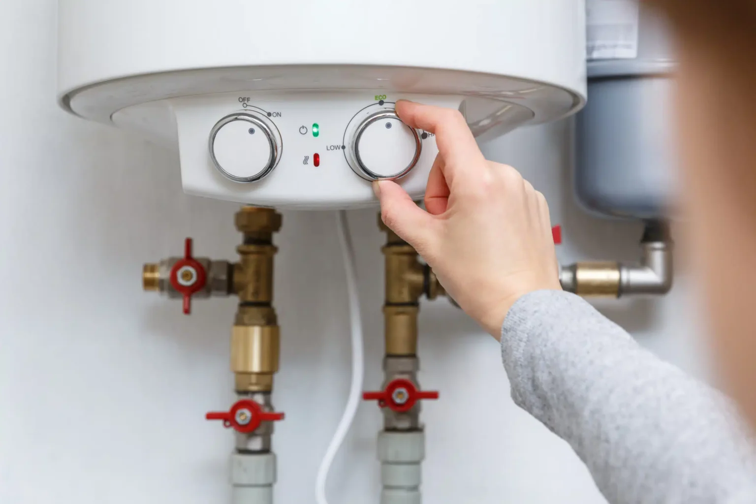 Homeowner adjusting the temperature controls on a water heater in Colton